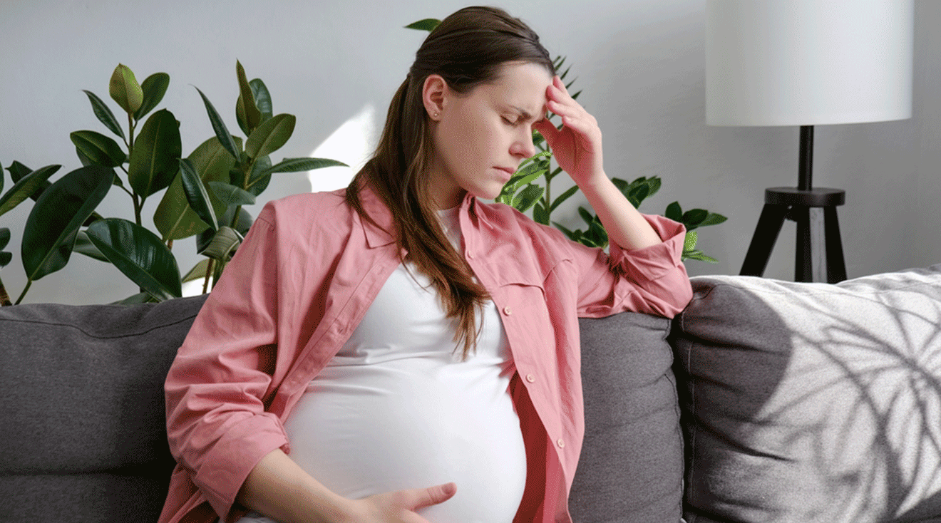 dizzy pregnant woman sitting on couch at home