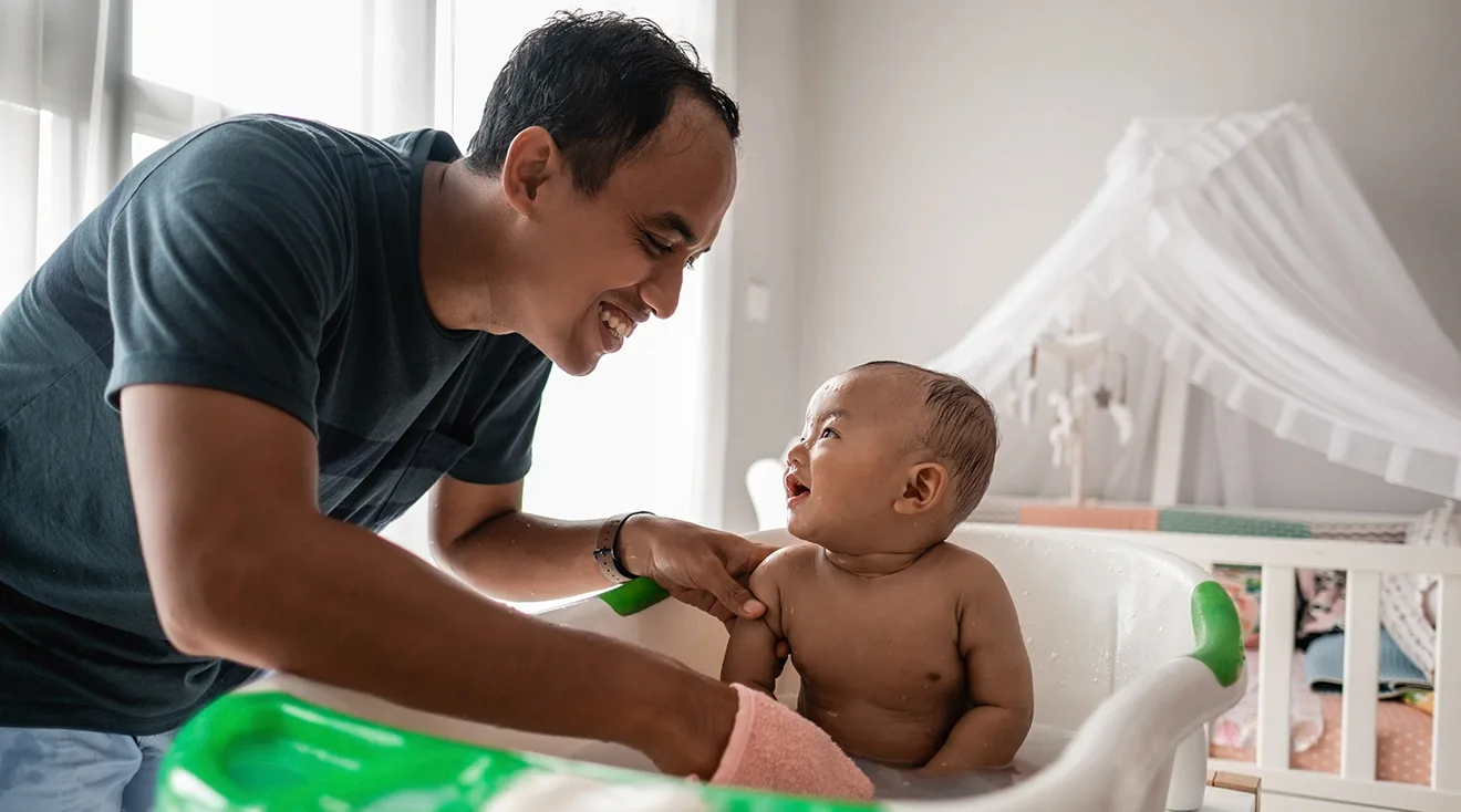 father washing baby in bath