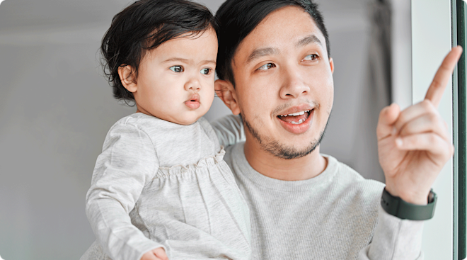 father pointing to something to teach baby how to speak