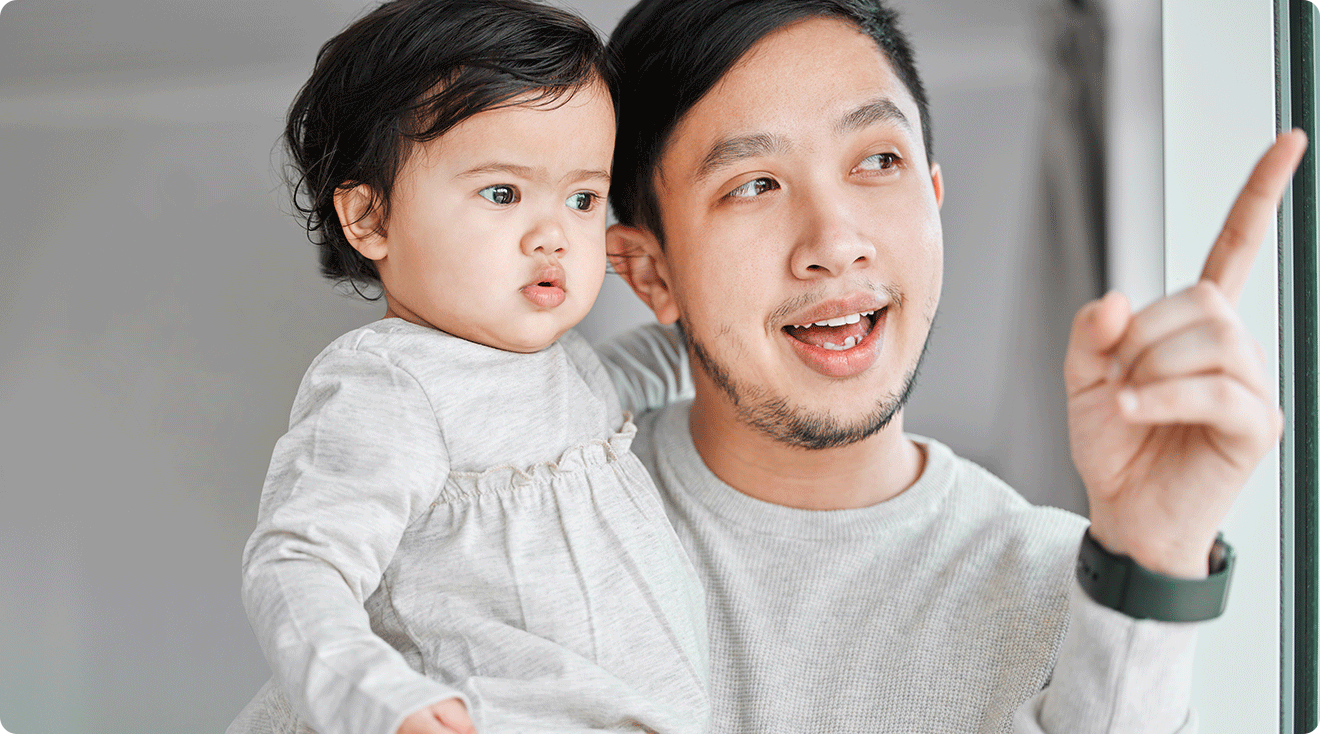 father pointing to something to teach baby how to speak