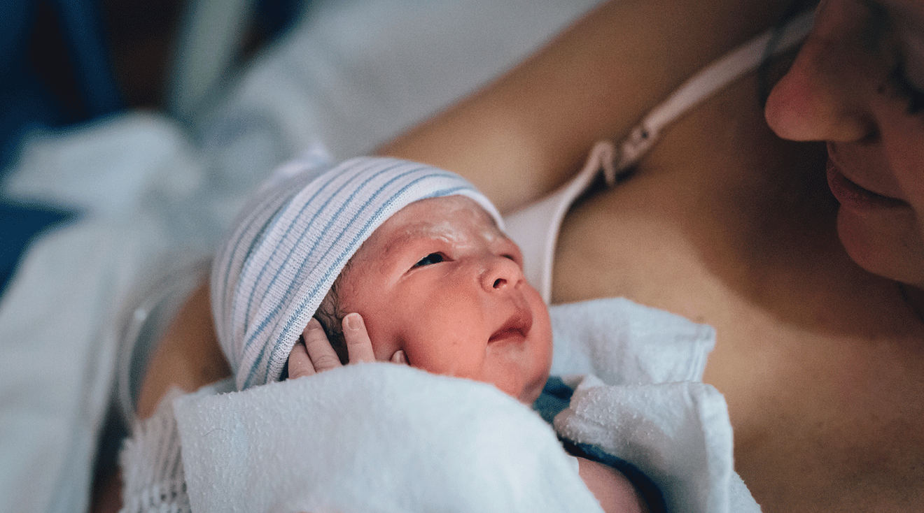 mom looking at newborn baby with vernix caseosa