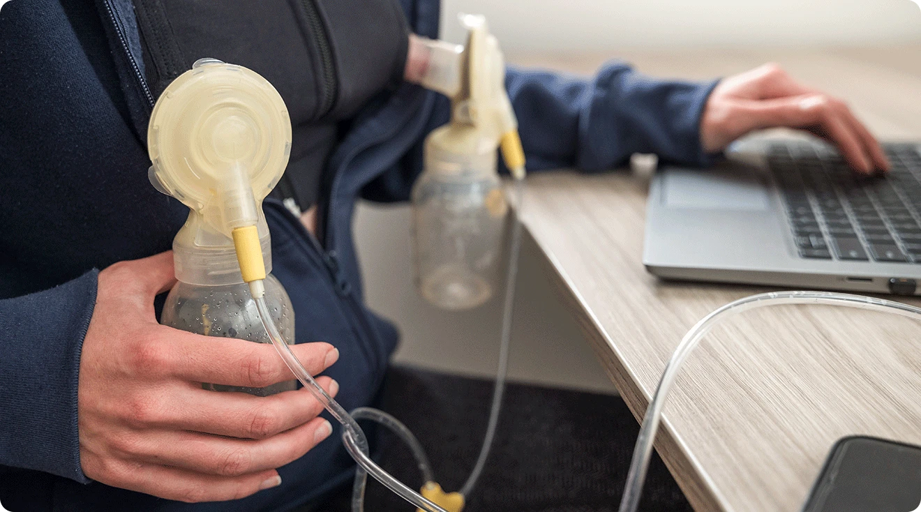 woman breast pumping while working on laptop