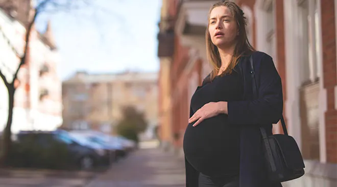 Pregnant woman outside with concerned look on her face.