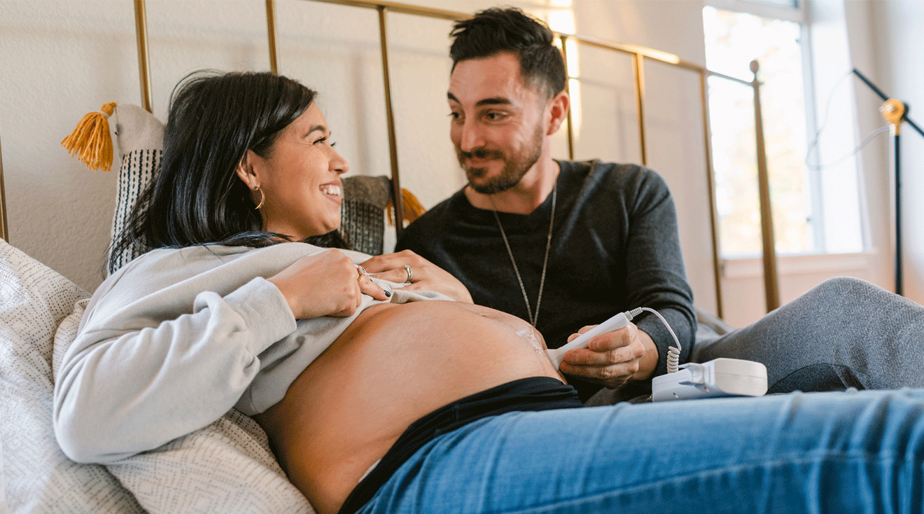 pregnant couple listening to baby's heartbeat with doppler device