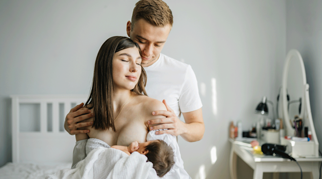 mom breastfeeding with husband at home