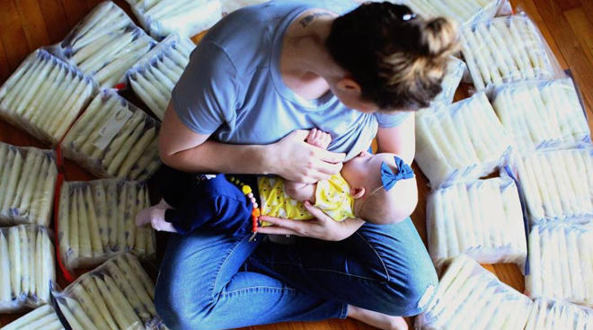 Woman holding her baby among packets of breast milk