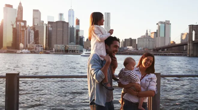family on vacation laughing in front of new york city skyline 