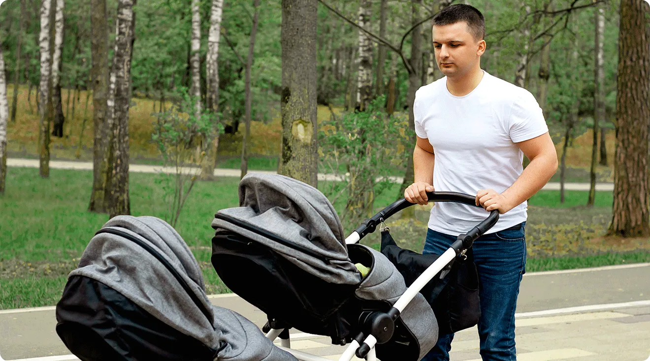 dad pushing a double stroller in the park