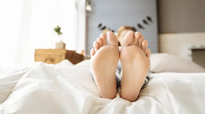 pregnant woman resting feet in bed