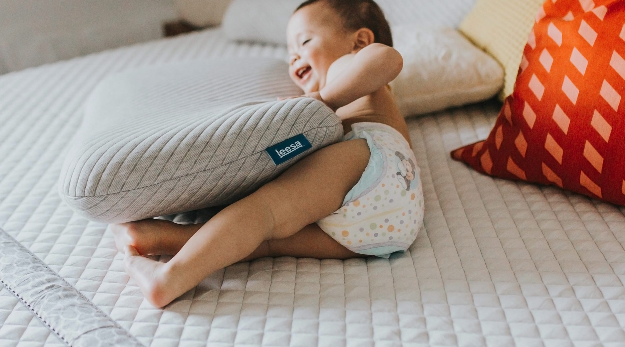 laughing baby wearing a diaper and playing on bed