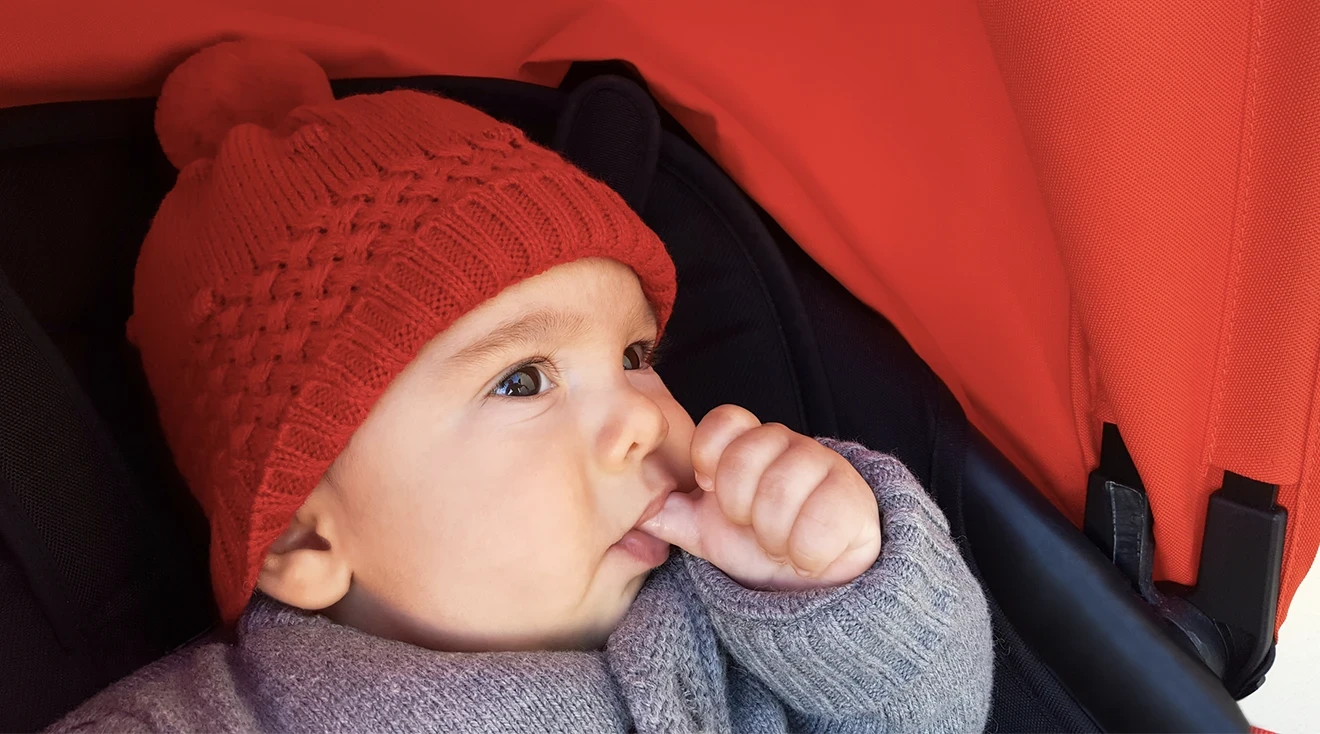 baby sucking thumb while sitting in stroller outside