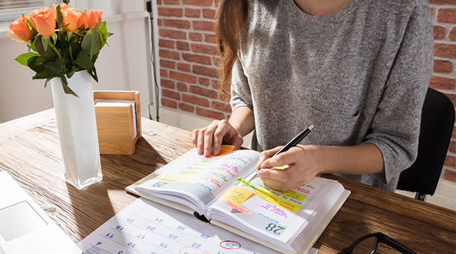 Woman sitting at desk and planning with notebook and calendar.