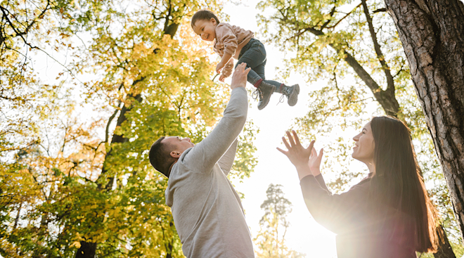 mom and dad playing with baby outside on fall day
