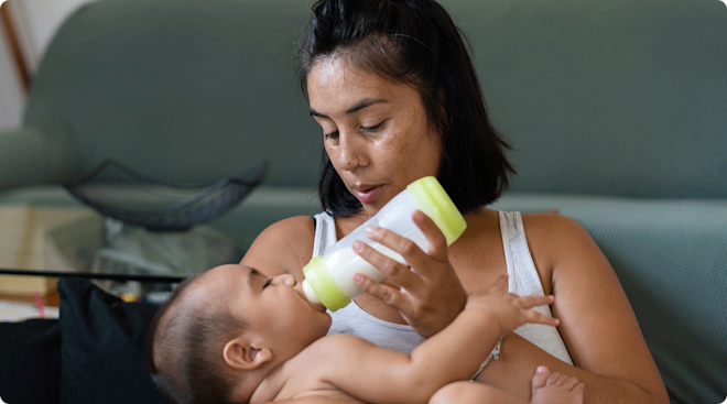 mom giving baby a bottle at home