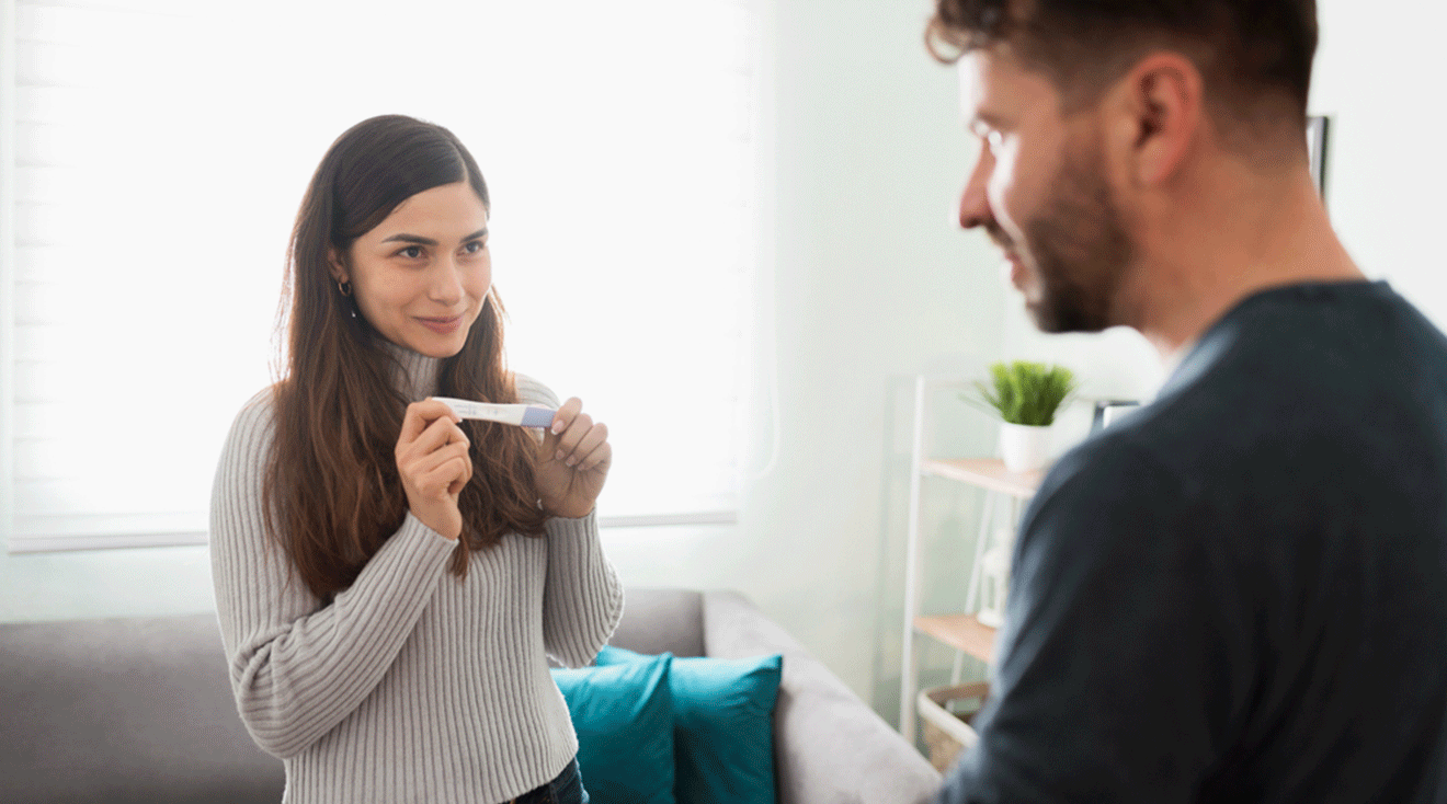 happy woman showing her partner a positive pregnancy test