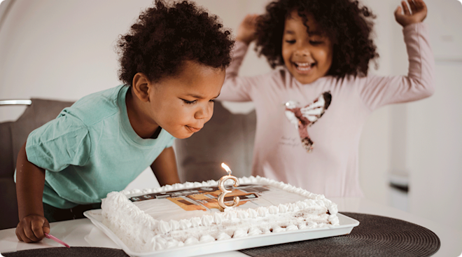 toddler turning 3 blowing out candles on third birthday cake