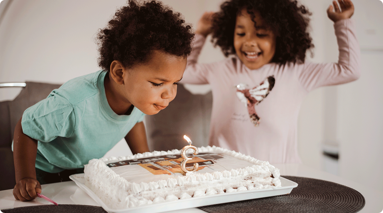toddler turning 3 blowing out candles on third birthday cake