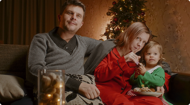 parents and toddler watching a christmas movie on the couch at home