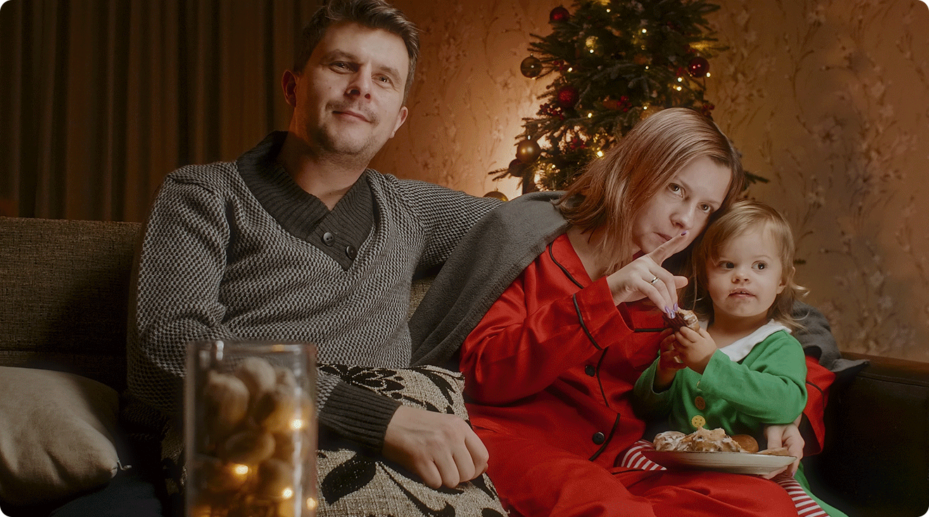 parents and toddler watching a christmas movie on the couch at home
