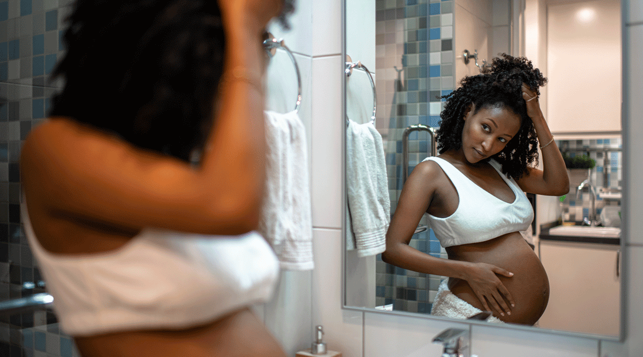 pregnant woman looking in bathroom mirror