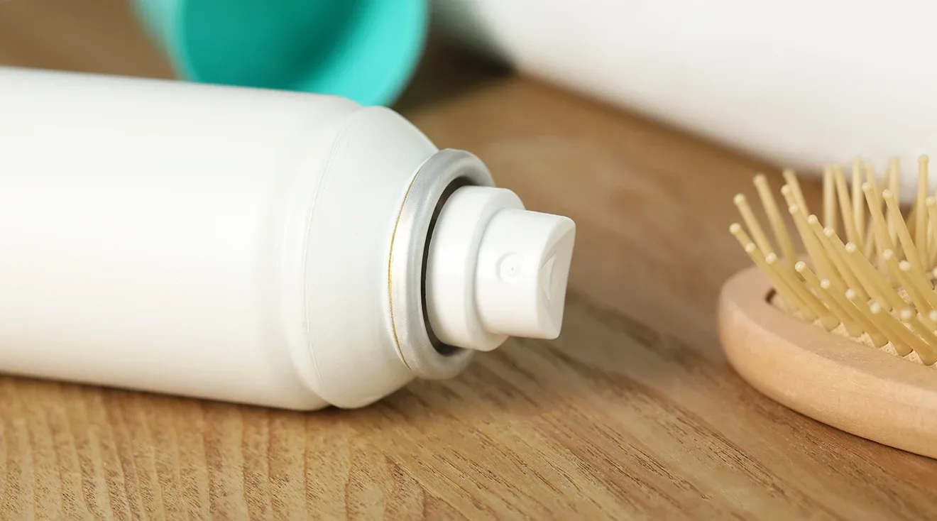 dry shampoo bottle on counter next to hair brush