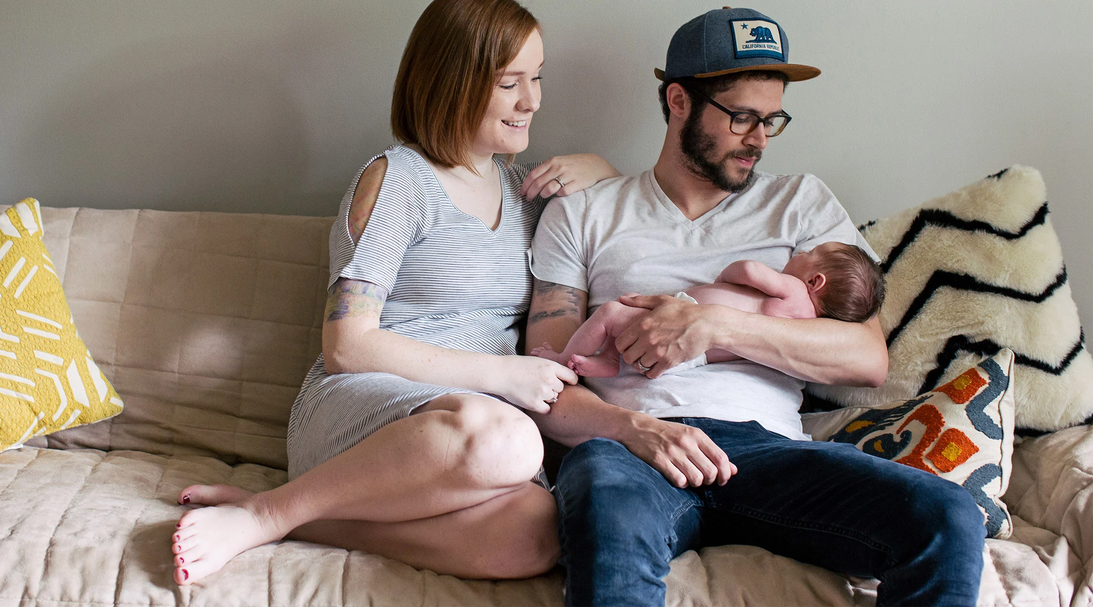 new parents at home staring lovingly at their newborn baby