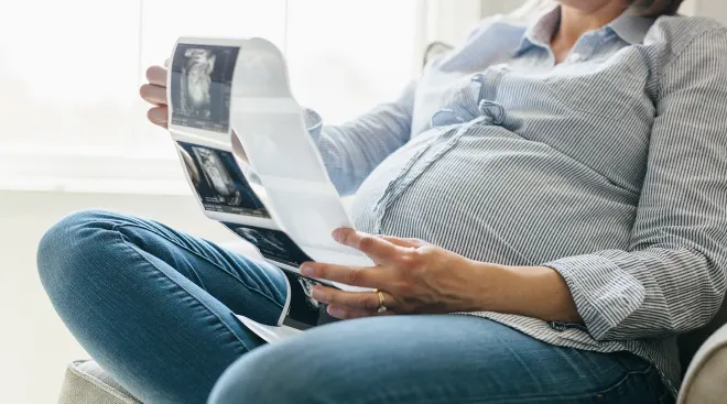 pregnant woman sitting at home looking at ultrasound photos