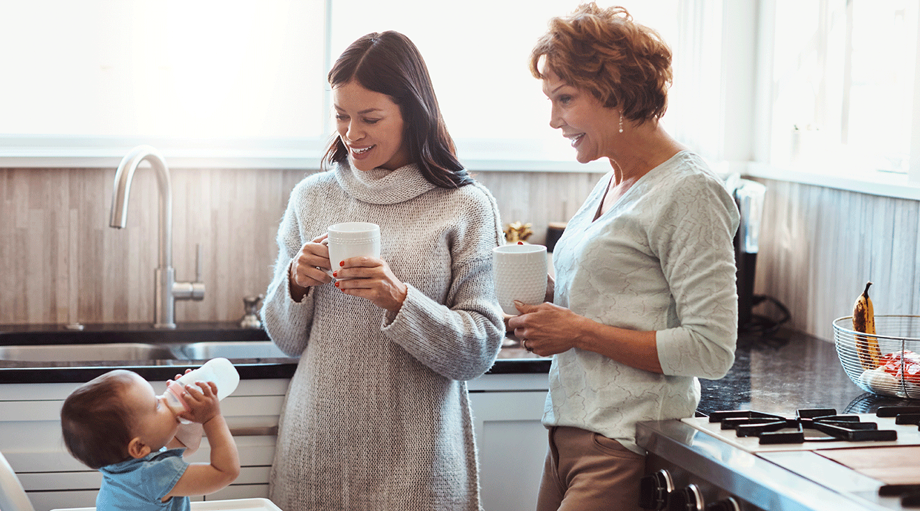 mom and grandma sitting with baby in kitchen