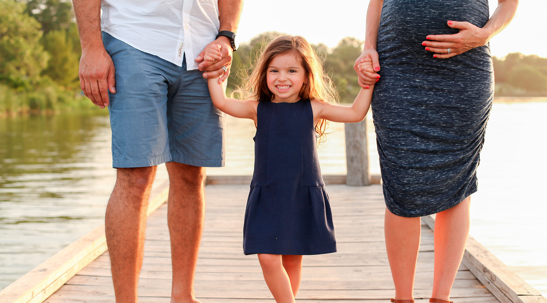 pregnant woman with husband and daughter outside on a dock