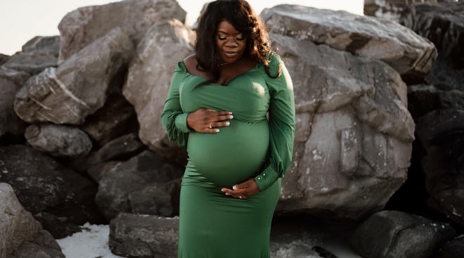 pregnant woman wearing dark green holiday dress at the beach