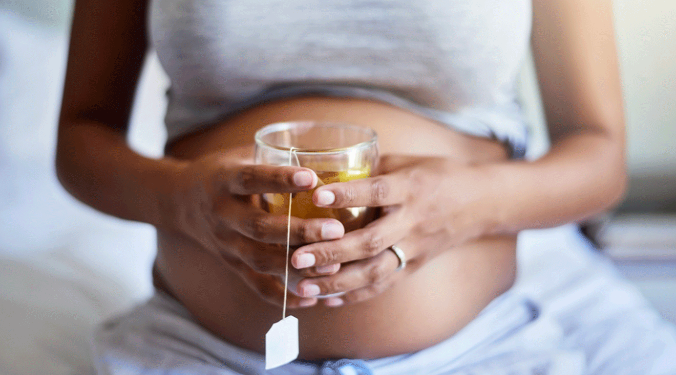 pregnant woman holding a cup of green tea