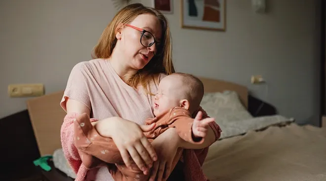 tired mother holding crying baby