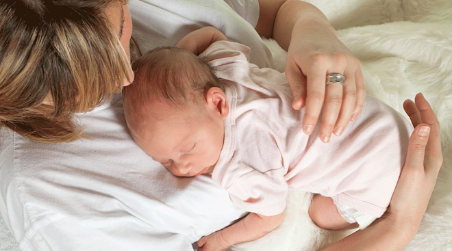 mother holding newborn baby at home