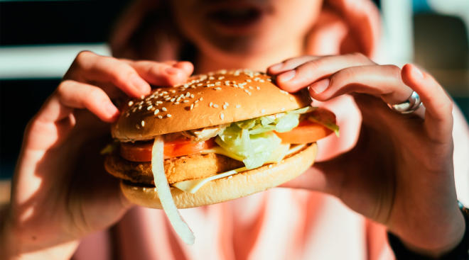 woman holding fast food burger 