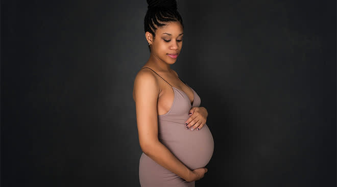 Pregnant woman standing and touching her large belly. 
