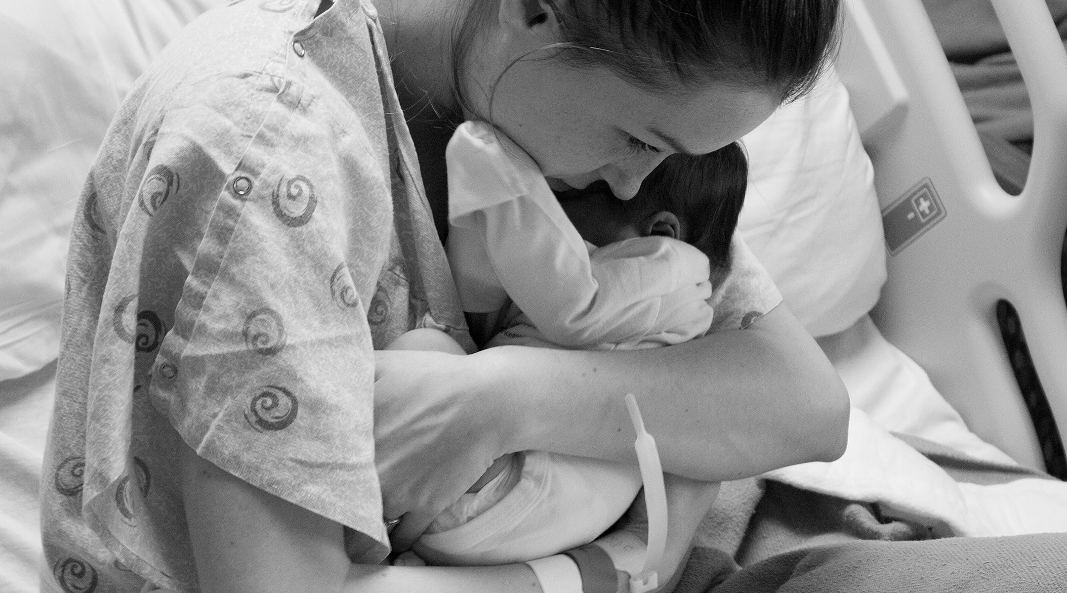 woman holds her newborn baby tightly after just giving birth