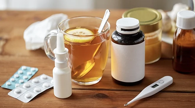 cold and flu medication and hot tea on wooden table at home