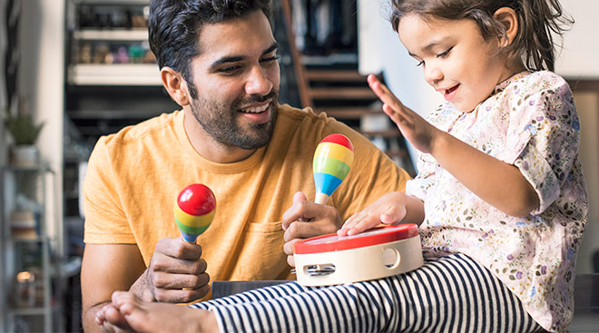 happy little girl and her dad playing with musical instruments