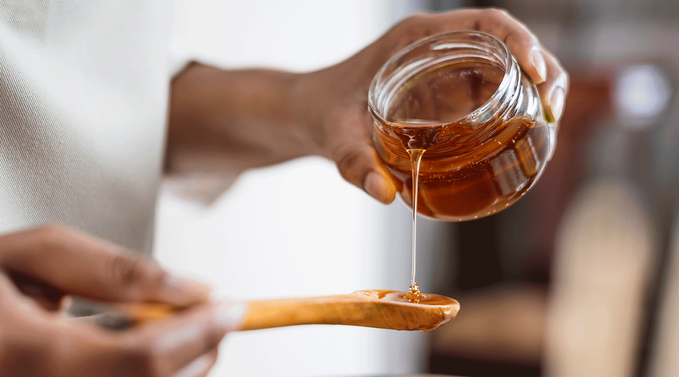 woman pouring honey onto spoon
