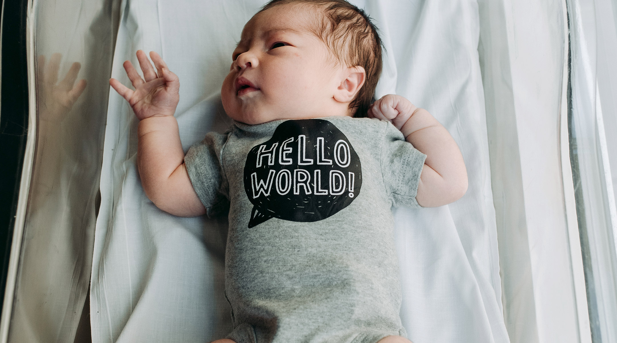 newborn baby in the hospital wearing a hello world onesie