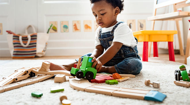 toddler playing in his room with wooden train set