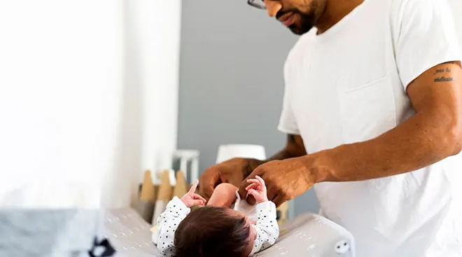 Dad changing his newborn's diaper.