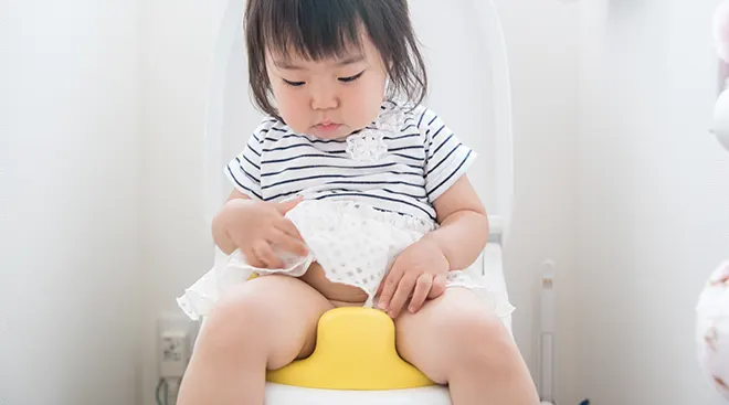 toddler girl sitting on toilet, potty training