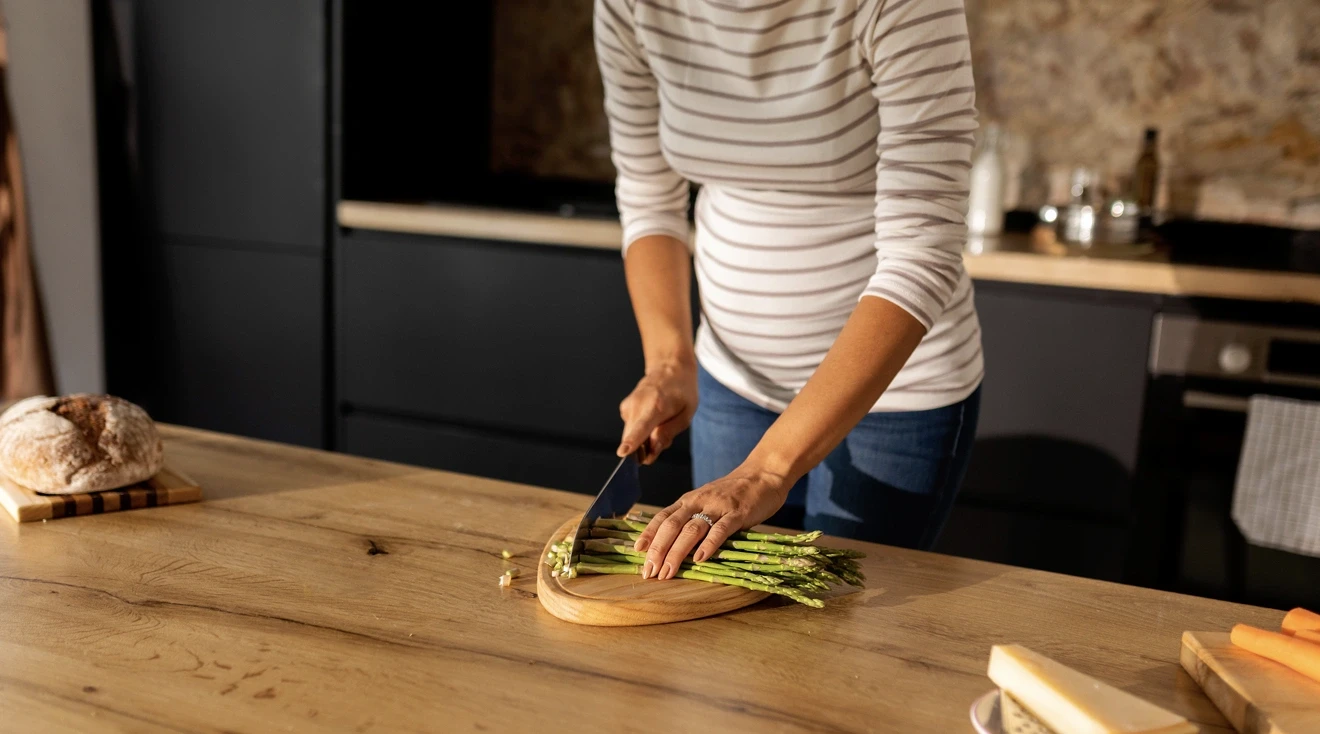 pregnant woman chopping asparagus at home for postpartum meal prep