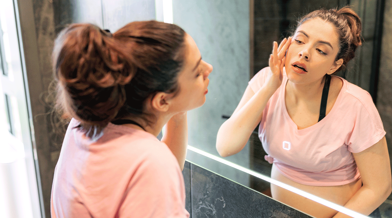 pregnant woman examining face in mirror