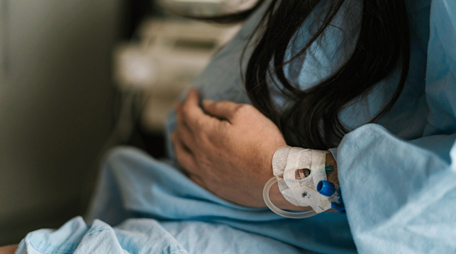 pregnant woman in labor wearing hospital gown and IV in hand
