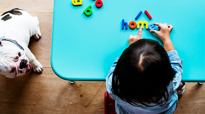 toddler at home playing with magnetic letters, spelling out home