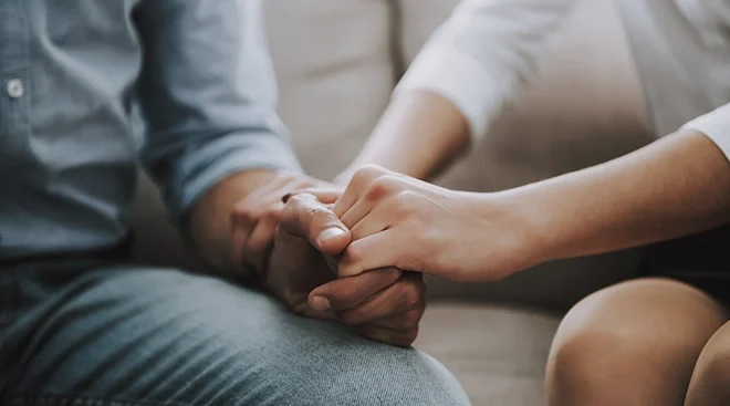 close up of couple holding hands while sitting on couch