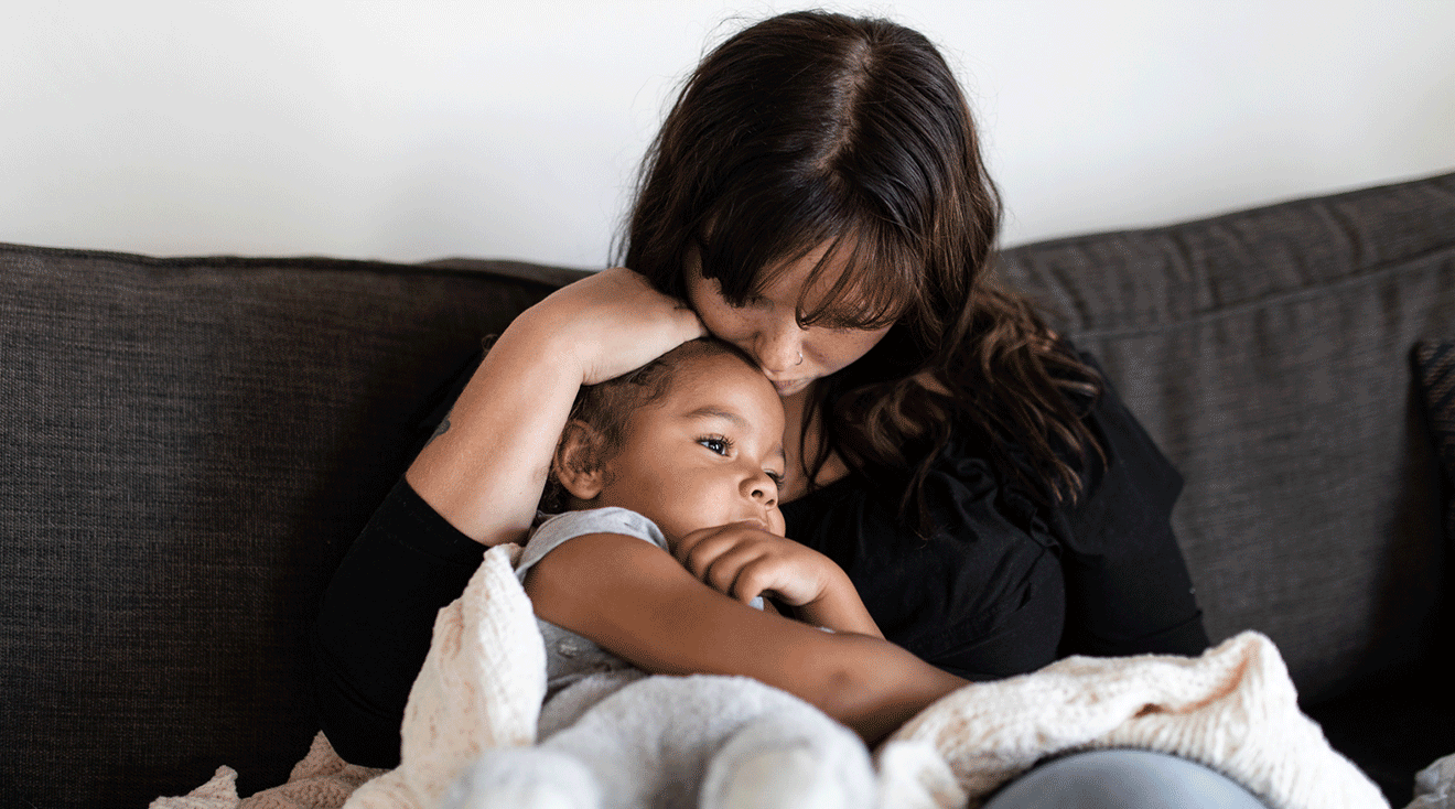 concerned mom comforting child on the couch at home