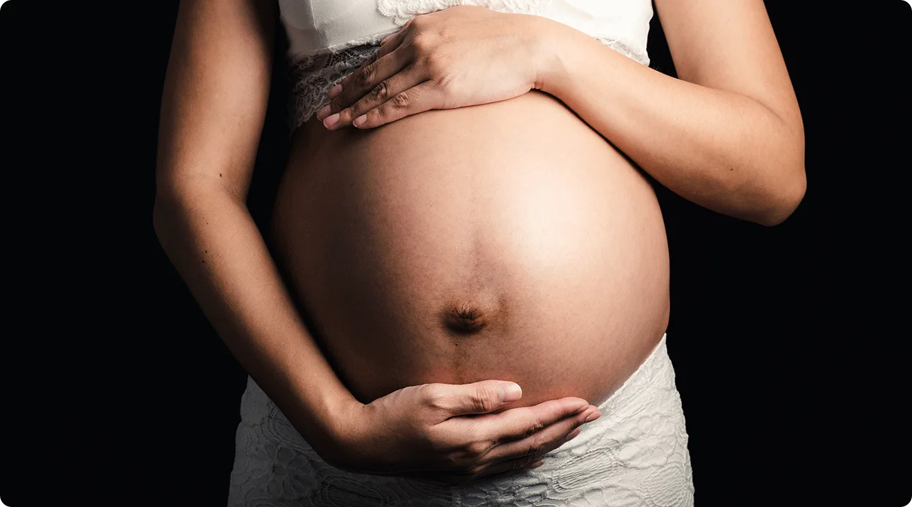 pregnant woman holding belly with dark background